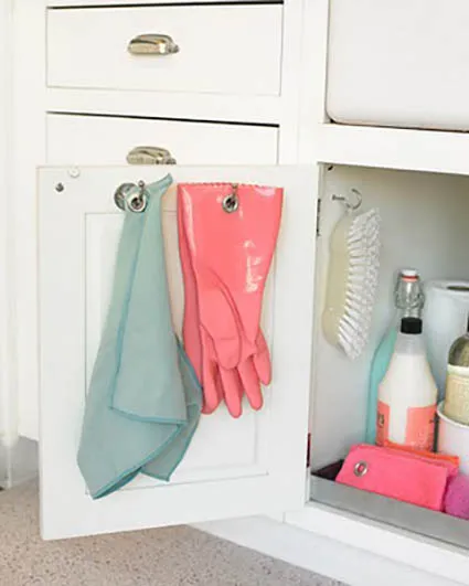 Cleaning supplies hung on hooks and on slide out shelf underneath sink