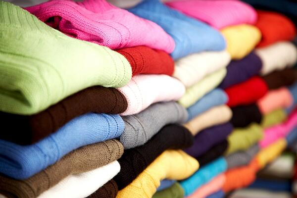 Colourful sweaters stacked neatly and folded on shelves