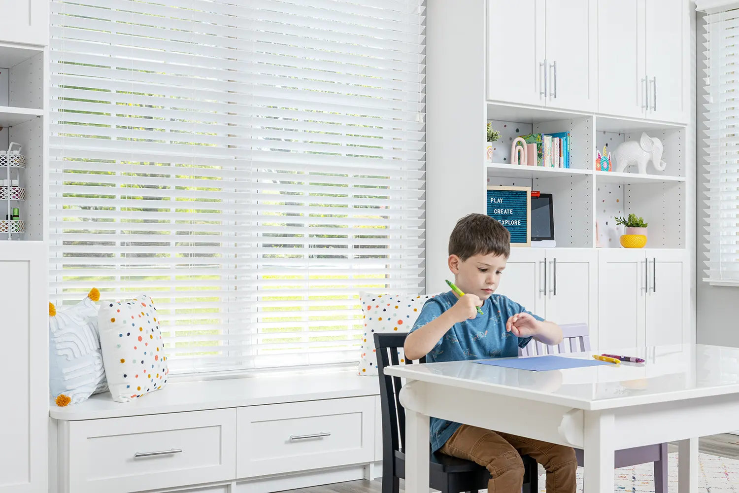 Child working on homework on playroom table with organized cabinets behind