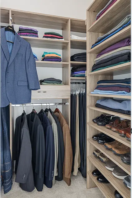 Reach in closet with shelves and jacket hanging on valet rod.