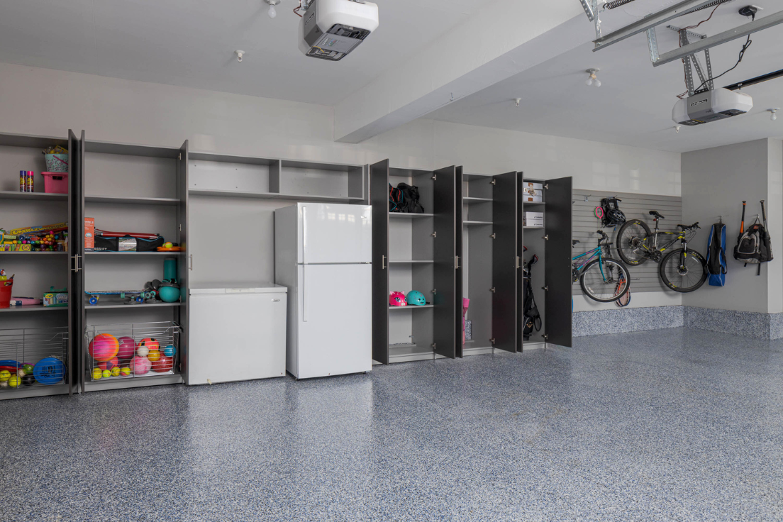 Organized garage with built-in cabinets, open shelving, bike hooks, and storage for sports gear.