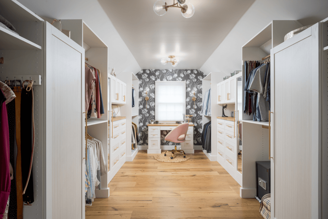 Custom walk-in closet with hanging storage, drawers, cabinetry, and a built-in vanity.