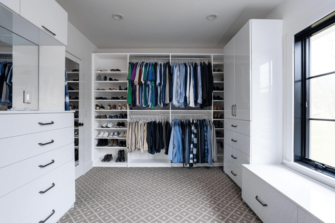 White walk-in closet with double hanging, shoe shelving, drawers, and a built-in window bench.