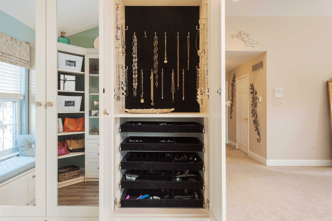 Custom jewelry cabinet with hanging necklace storage and slide-out velvet-lined trays.