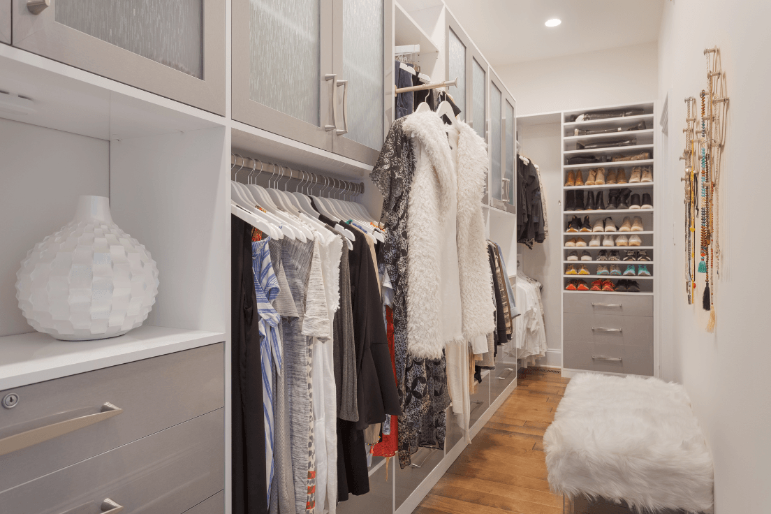 Finished custom walk-in closet with hanging storage, shoe shelving, drawers, upper cabinets, and a bench
